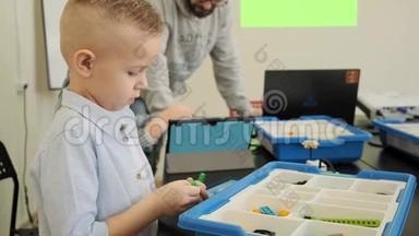 好奇的白种人孩子在慢动作课堂上体验如何构建塑料机器人玩具